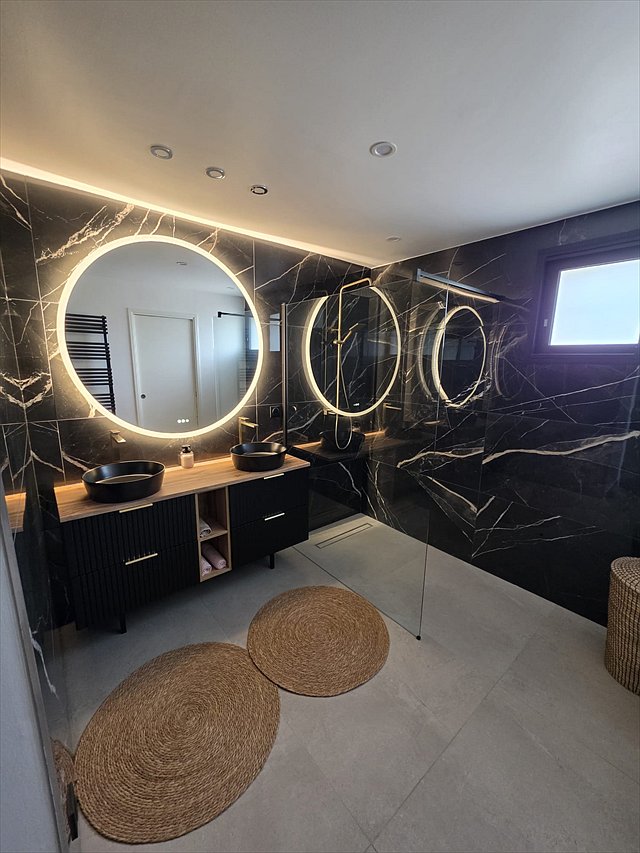 Salle de bains rénovée : double vasque, robinetterie dorée et douche à l'italienne